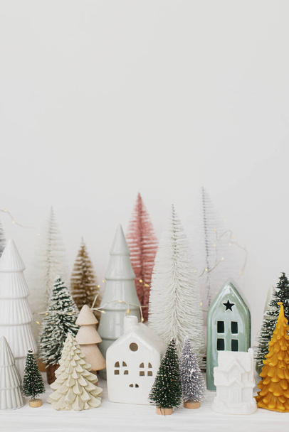 З Різдвом та Різдвом Христовим! Сучасна різдвяна сцена, мініатюрне затишне засніжене село. Стильні маленькі ялинки та прикраси будинків на білому столі. Зимовий банер, скандинавський декор
 - Фото, зображення
