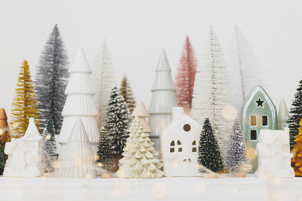 Boldog Karácsonyt és Kellemes Ünnepeket! Modern karácsonyi jelenet, miniatűr hangulatos havas falu. Stílusos kis karácsonyfák és házak dekorációk fehér asztalon. Téli zászló, skandináv dekoráció - Fotó, kép