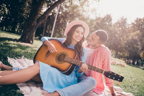 Photo of cute dreamy two people together wear casual outfits playing guitar sitting checkered blanket outside garden. - 写真・画像
