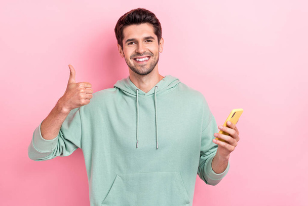 Photo of youngster positive successful man showing thumb up like recommend video smartphone blogger nice quality ad isolated on pink color background. - Фото, зображення