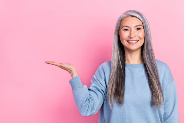 Photo of adorable cute lady pensioner dressed blue pullover holding arm empty space isolated pink color background. - Φωτογραφία, εικόνα