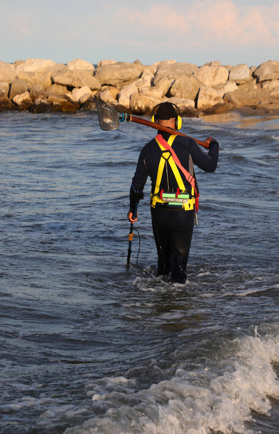 Homme récupérant en cherchant avec le détecteur de métaux des objets perdus dans la mer près du rivage - Photo, image