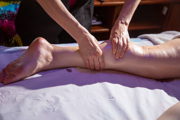  Sedyede yatan bir hastanın bacaklarına masaj yapan bir terapist.. - Fotoğraf, Görsel
