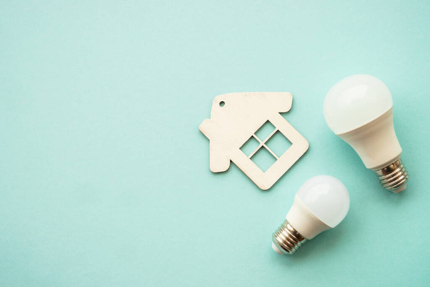 Saving electricity. Paying bills. LED lamp, wire with plug and house at color background. - Photo, Image