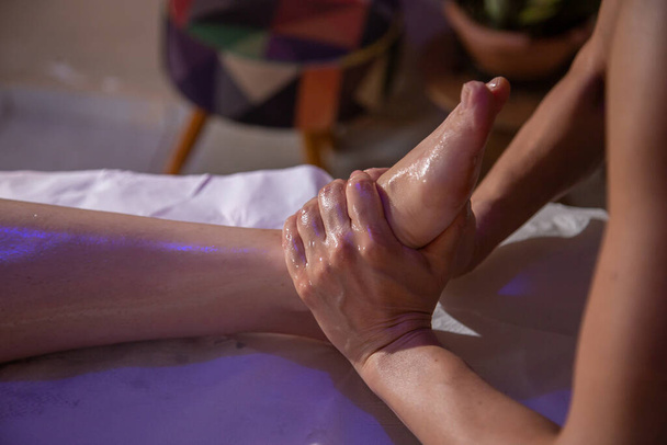 Un thérapeute donne un massage des pieds à un patient allongé sur une civière. - Photo, image