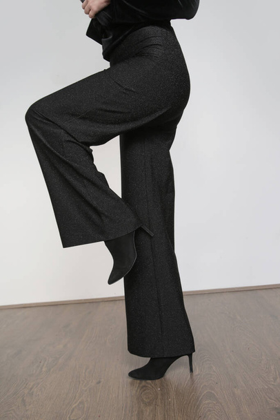Σειρά φωτογραφιών από στούντιο γυναικείου μοντέλου με φαρδύ μαύρο κομψό παντελόνι και μαύρα ψηλά τακούνια. - Φωτογραφία, εικόνα