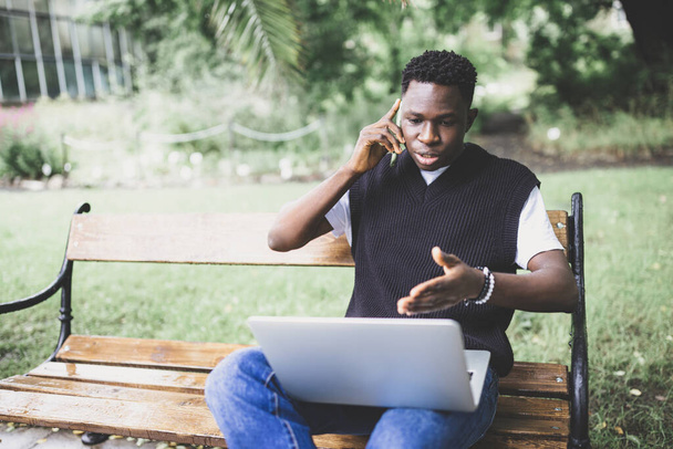 Νεαρός Αφρικανός που μιλάει στο τηλέφωνο διαφωνώντας για τον υπολογιστή, αγχωμένος, ανικανοποίητος. Απογοητευμένος, μπερδεμένος, θυμωμένος αρσενικό υποστηρίζοντας με την τεχνική online υποστήριξη ή την εξυπηρέτηση πελατών. Κακή έννοια σύνδεσης - Φωτογραφία, εικόνα