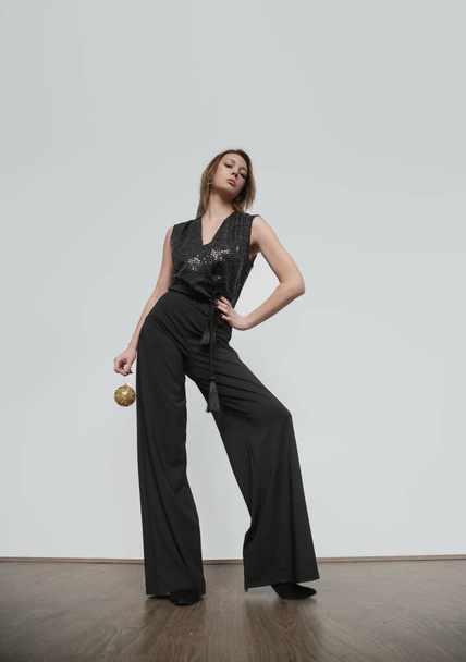 Serie of studio photos of female model wearing sparkling black jumpsuit, simple and effective outfit for New Year's Eve party. Holidays season clothing. - Foto, Imagen