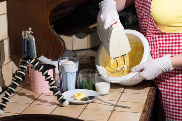 donna che cucina il muffin agli spinaci passo dopo passo, impastando gli ingredienti con il mixer, registrando video sul cellulare per i social media. Foto di alta qualità - Foto, immagini