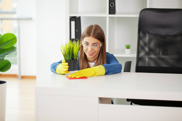 黄色の手袋の女性がオフィスをきれいにする. - 写真・画像