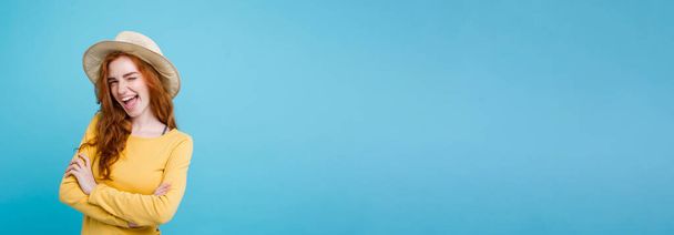 Reisekonzept - Nahaufnahme Porträt junge schöne attraktive Rothaarmädchen mit trendigen Hut und Sonnenbrille lächelnd. blauer Pastellhintergrund. Kopierraum. - Foto, Bild