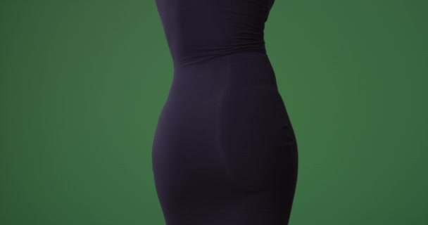 Dietro una donna nera sexy in un abito nero stretto che balla sullo schermo verde. Sullo schermo verde da digitare o comporre. - Filmati, video