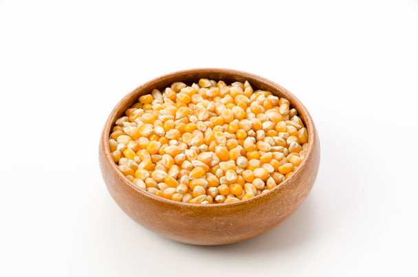 Семена попкорна в деревянной чаше на белом фоне.  - Фото, изображение