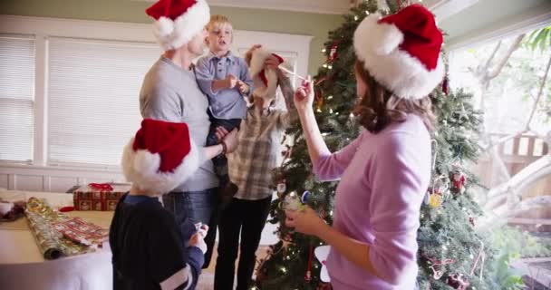 Preciosa familia de pie junto a un árbol de Navidad - Metraje, vídeo