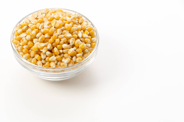 Ungeöffnete Popcorn-Samen in transparenter Glasschale auf weißem Hintergrund.  - Foto, Bild
