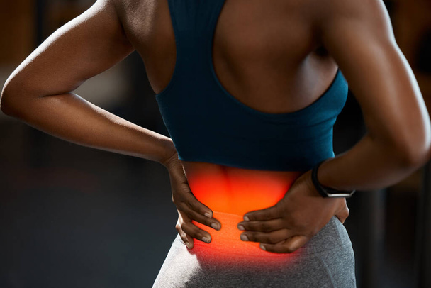Shes picked up a lower back injury. Rearview shot of an unrecognizable and athletic young woman holding her lower back in pain while at the gym - Fotoğraf, Görsel