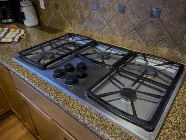 widok na piękny blat kuchenki gazowej z czarnymi gałkami na kwadratowy splash - Zdjęcie, obraz