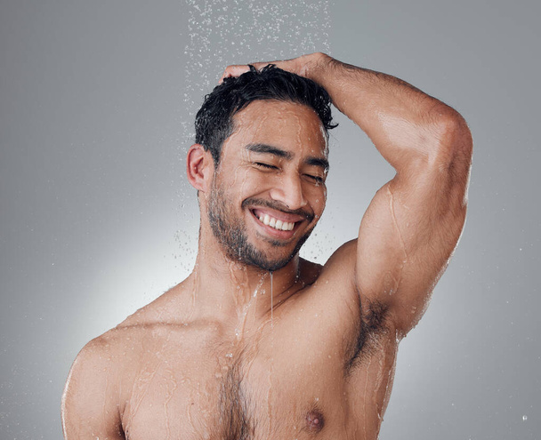 A zuhany az ő boldog helye. egy fiatal férfi mossa a haját a zuhany alatt egy szürke háttér - Fotó, kép