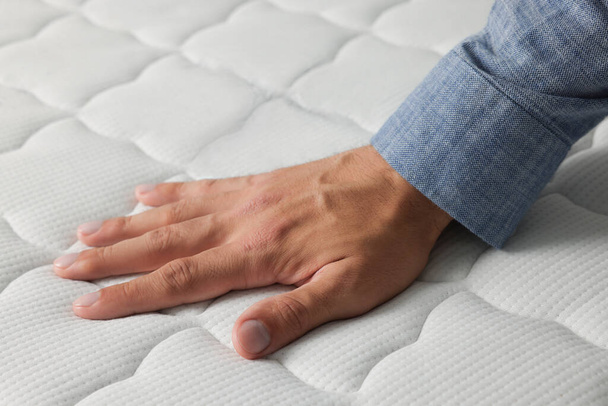 Man touching soft white mattress, closeup view - Foto, afbeelding