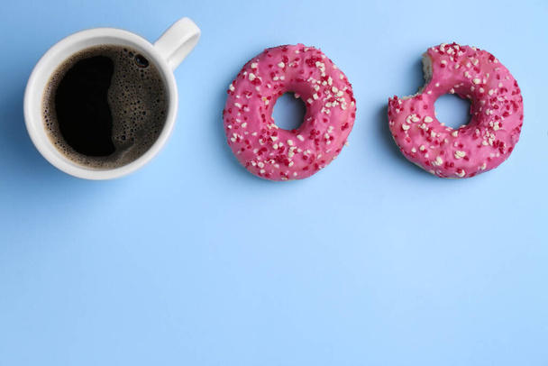 Tasty donuts and cup of coffee on light blue background, flat lay. Space for text - Фото, изображение