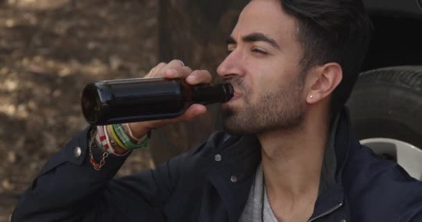 Atractivo hombre hispano bebiendo cerveza mientras espera ayuda en la carretera - Imágenes, Vídeo