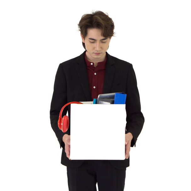 Joven hombre de negocios asiático en traje negro se sienten tristes, estresados e infelices cara sosteniendo caja de papel de pertenencias recogidas de la oficina en el día de ser despedido. Idea para desempleados, crisis laboral. - Foto, Imagen