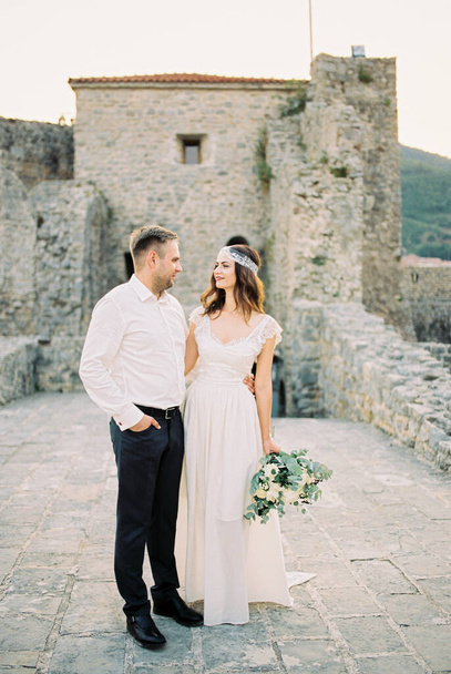 Bride and groom stand embracing on the bridge near the ruins of the old fortress. High quality photo - Photo, image