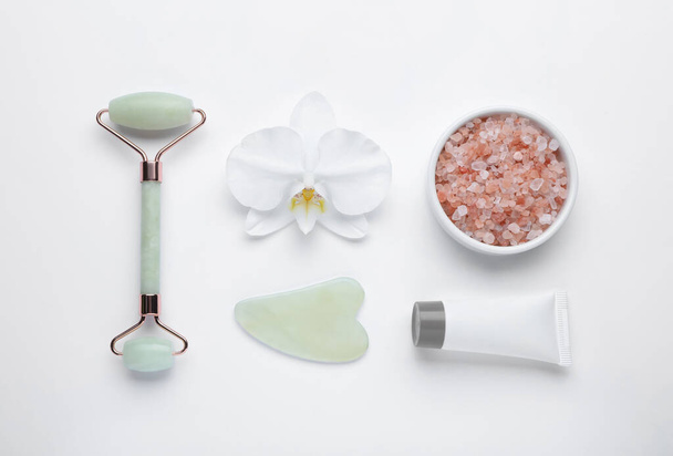 Flat lay composition with gua sha stone and face roller on white background - Foto, afbeelding