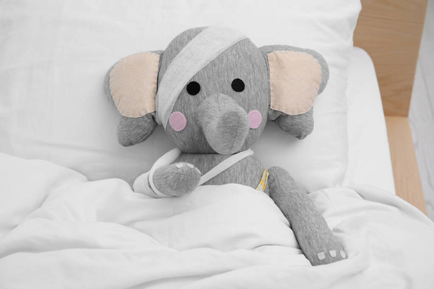Toy elephant with bandages lying in bed - Foto, Imagem