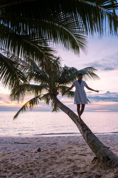 Тайские азиатки в шляпе, смотрящие на закат с тропического пляжа у океана, тропического острова Ко Куд (Koh Kood) или Ко Кут (Koh Kut Thailand).  - Фото, изображение