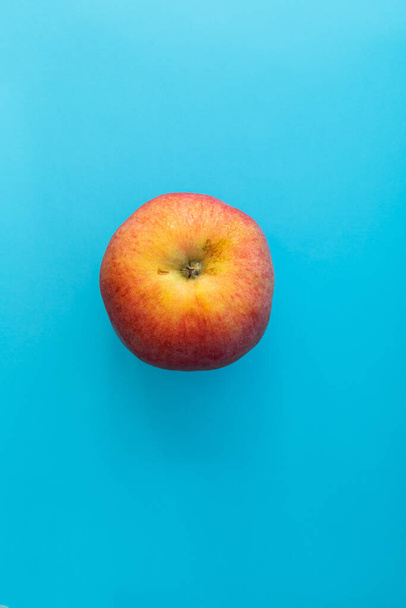 青い背景にジューシーな赤いリンゴ、被写体の食べ物が撃たれました - 写真・画像