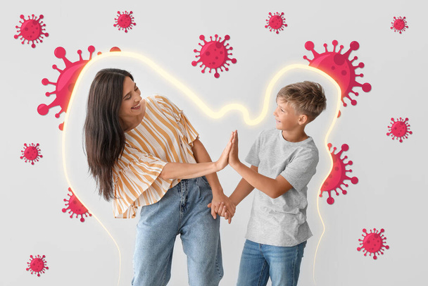 Счастливая женщина и ее маленький сын дают друг другу пять на светлом фоне. Концепция сильного иммунитета - Фото, изображение