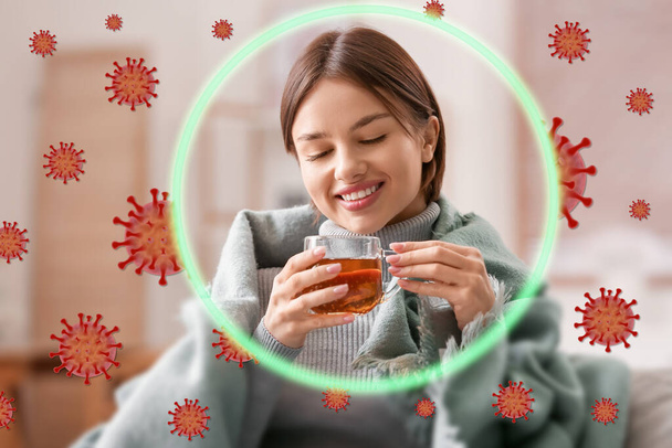 Een gelukkige jonge vrouw die thuis warme thee drinkt. Concept van een sterke immuniteit - Foto, afbeelding