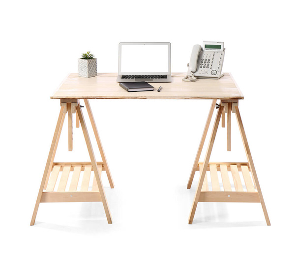 Escritorio de pie de madera con portátil, planta de interior, portátil y teléfono fijo sobre fondo blanco - Foto, Imagen