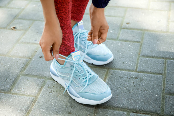 Vrouw in stijlvolle sneakers strikken schoen kant buiten - Foto, afbeelding