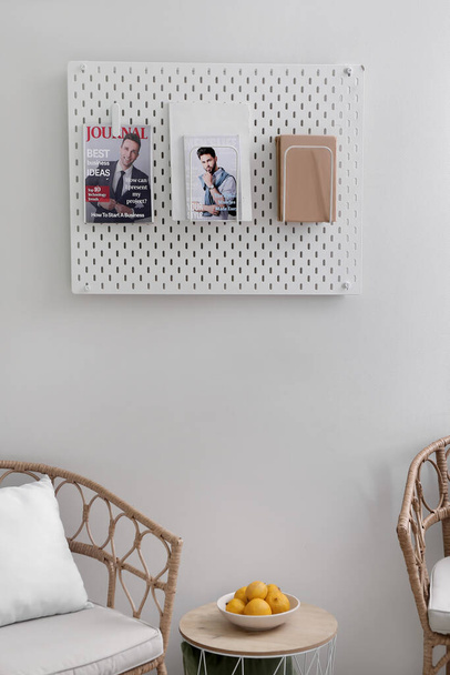 Pegboard con revistas y libro sobre pared de luz en la habitación - Foto, imagen
