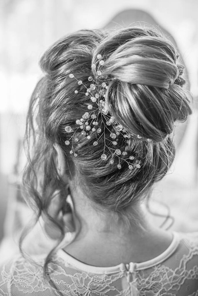 Young beautiful bride with wedding bridal hairstyle with pearls and crystals  near the boudoir table in the bedroom. wedding morning - Fotografie, Obrázek