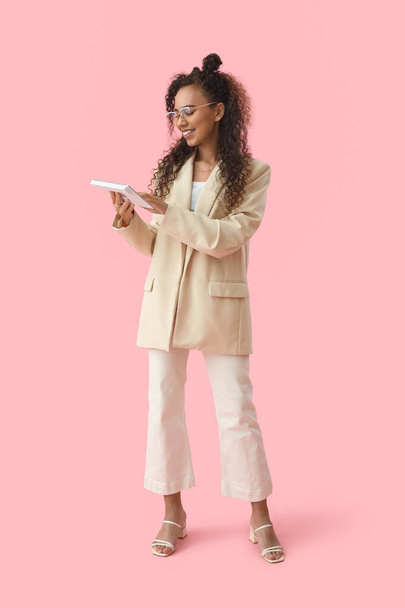 Young African-American woman with computer keyboard on pink background - Photo, Image