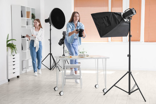 Fotógrafa feminina com assistente trabalhando em estúdio moderno - Foto, Imagem