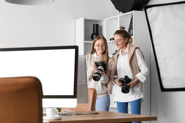 Female photographer and her assistant working in modern studio - Foto, imagen
