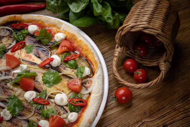 pizza with eggplant, cheese, tomatoes and chili peppers in a restaurant - Foto, Imagen