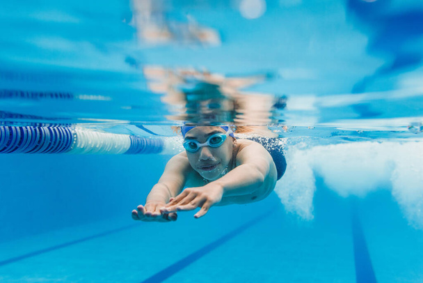 jovem adolescente latino atleta nadador vestindo boné e óculos em um treinamento subaquático de natação Na piscina no México América Latina - Foto, Imagem