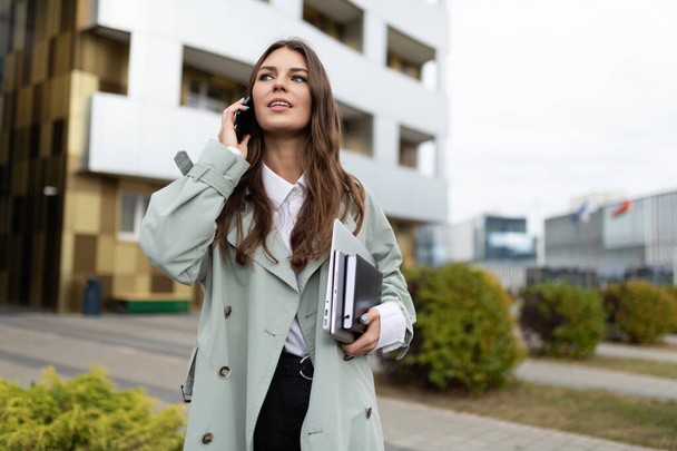 молода стильна жінка говорить на мобільному телефоні на фоні міста. - Фото, зображення