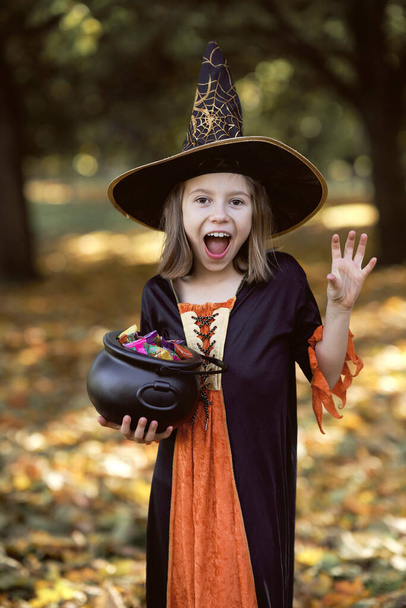 Vertical image of girl in witch outfit and standing in the woods - Φωτογραφία, εικόνα