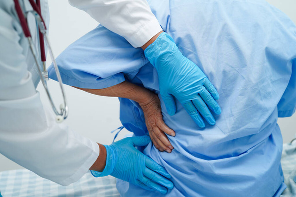 Γιατρός εξετάσει και τη θεραπεία ασιατική ηλικιωμένος ασθενής μυϊκό πόνο στην πλάτη πρόβλημα και φυσιοθεραπεία στο νοσοκομείο. - Φωτογραφία, εικόνα