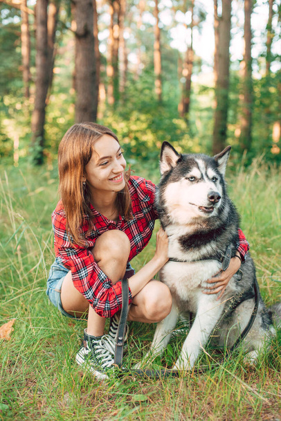 teenage girl playing and having fun with her siberian husky dog. Girl with dog in the forest - Foto, imagen