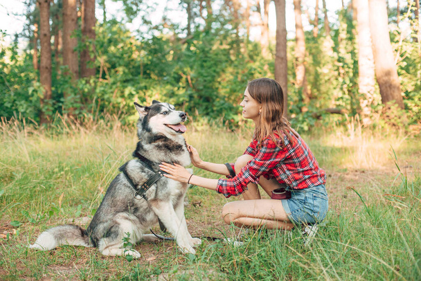 adolescente jugando y divirtiéndose con su perro husky siberiano. Chica con perro en el bosque - Foto, imagen
