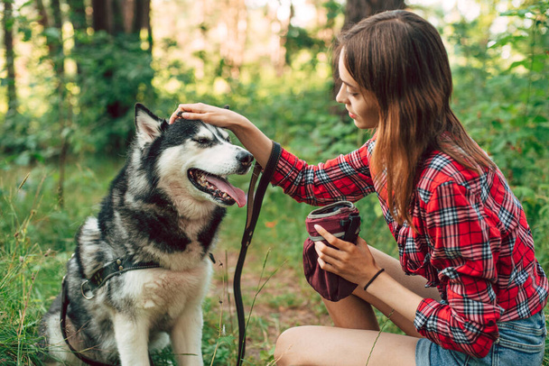 teenage girl playing and having fun with her siberian husky dog. Girl with dog in the forest - Foto, immagini