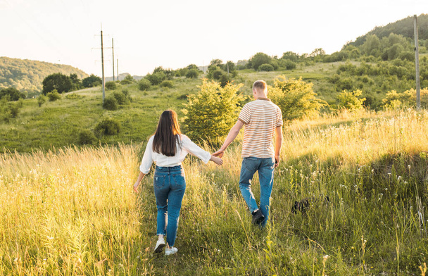young happy couple having fun with their french bulldog outdoors in the countryside during beautiful sunset - Fotografie, Obrázek