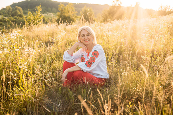 portrait of happy joyfull mature woman in countryside during beautiful sunset - Fotó, kép